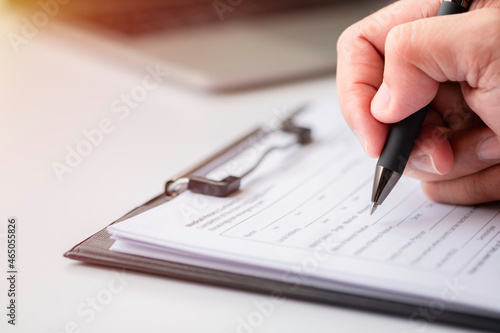 Image of Hand using writing pen with questionnaire or paperwork survey question filling in business company personal information form checklist document.