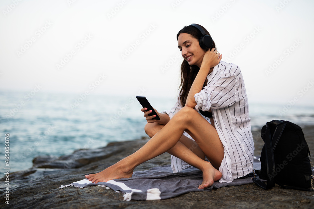  Hot woman relaxing on the sandy beach. Beautiful woman with headphones listening the music.
