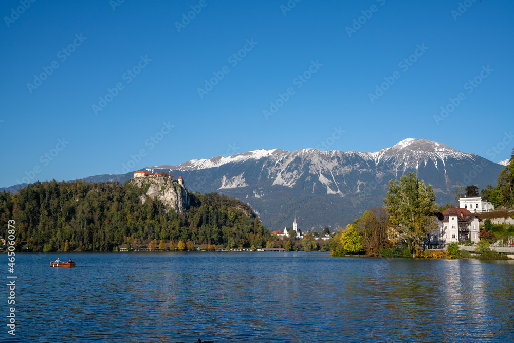 view of Lake Bled with the Bled Castle and village in autumn and snow-covered Julian Alps in the background