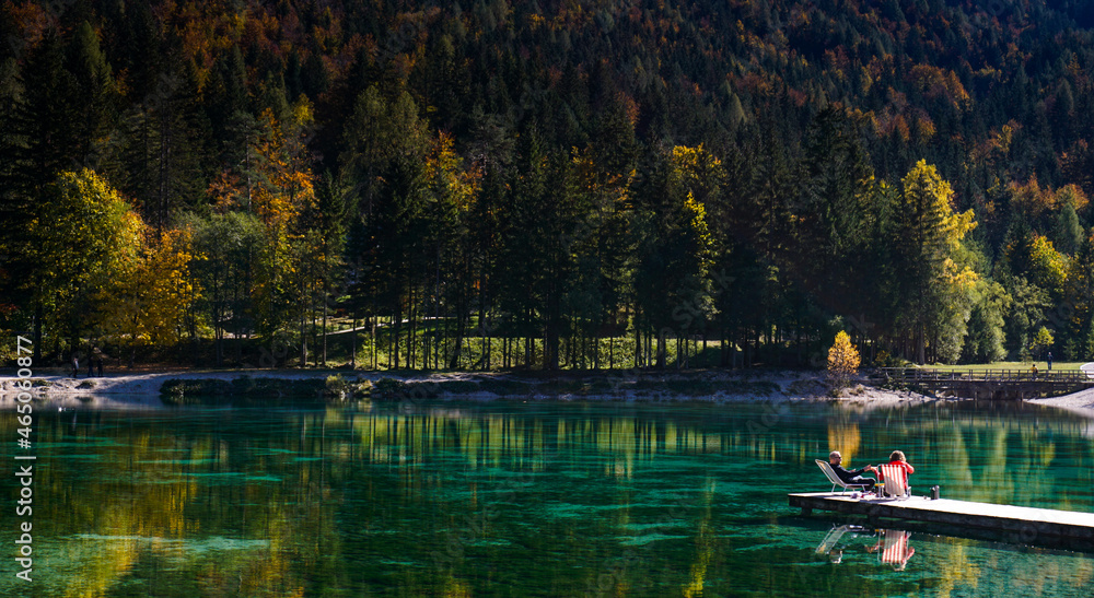 tourists enjoy relaxing on the wooden dock at Lake Jasna in the Slovenian Alps