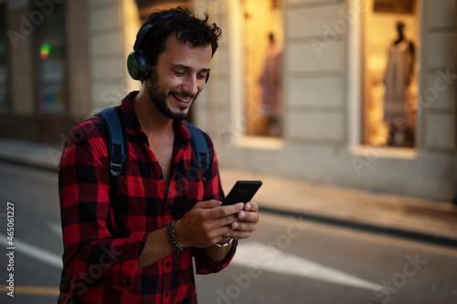 Young man listening to music. Urban fashion man with headphones enjoying the city.