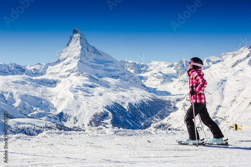 female skier resting on top of the mountain observing nature at ski resort on a beautiful sunny winter day. Matterhorn. Swiss Alps