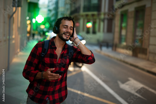 Young man listening to music. Urban fashion man with headphones enjoying the city. © Jelena