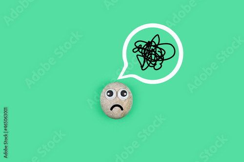 Character from a pebble with a sad face with a tangle of thoughts in its head. Character in search of ideas