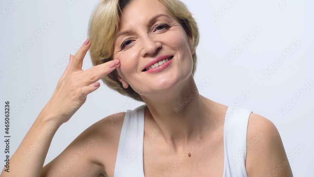 joyful middle aged woman with perfect skin touching face while smiling at camera isolated on white. joyful middle aged woman with perfect skin touching face while smiling at camera isolated on white.