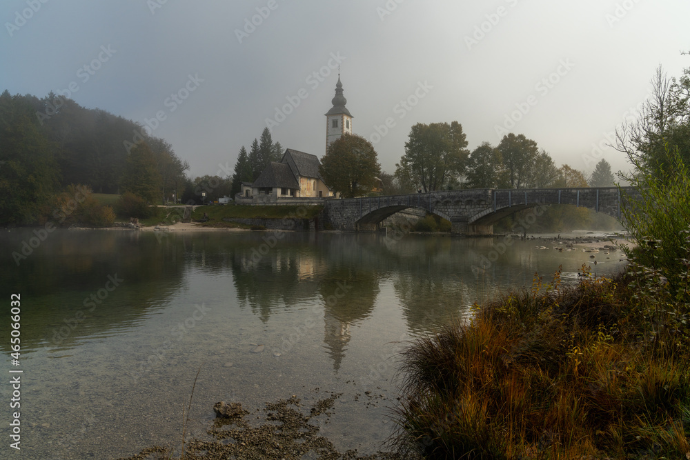 view of the Church of Saint John the Baptist on Lake Bohinj in Slovenia in late autumn