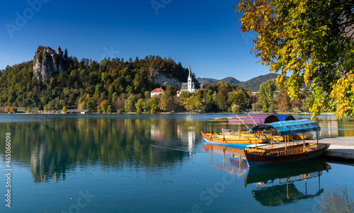 view of Lake Bled with the Bled Castle and village in autumn and snow-covered Julian Alps in the background