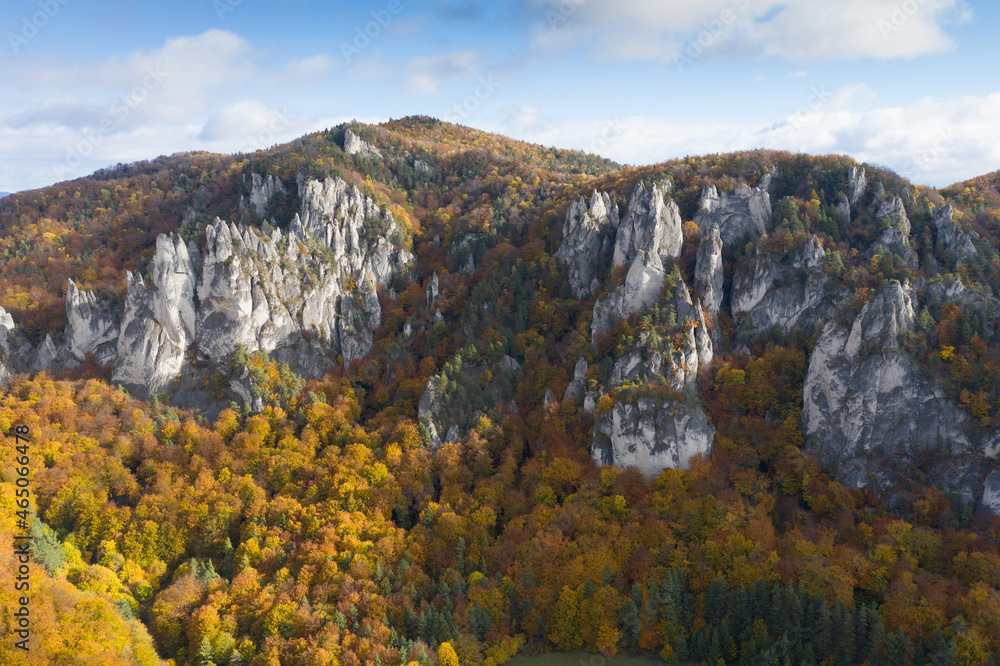 Scenic landscape in Sulov, Slovakia, on beautiful autumn sunrise with colorful leaves on trees in forest and bizarre pointy rocks on mountains and slight mist in the valleys and dramatic clouds on sky