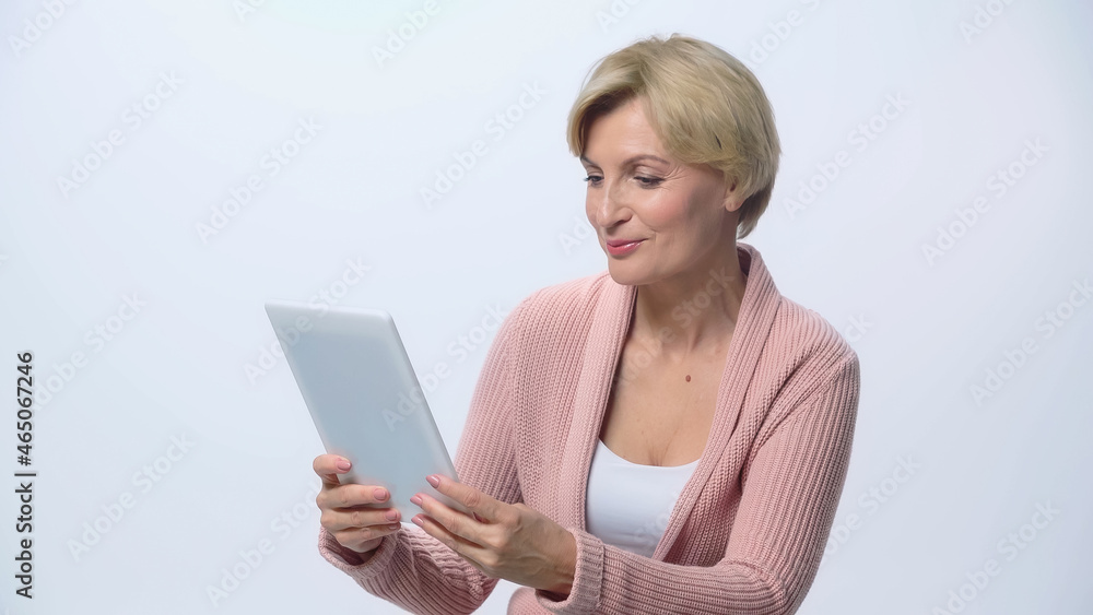 positive middle aged woman looking at digital tablet isolated on white. positive middle aged woman looking at digital tablet isolated on white.