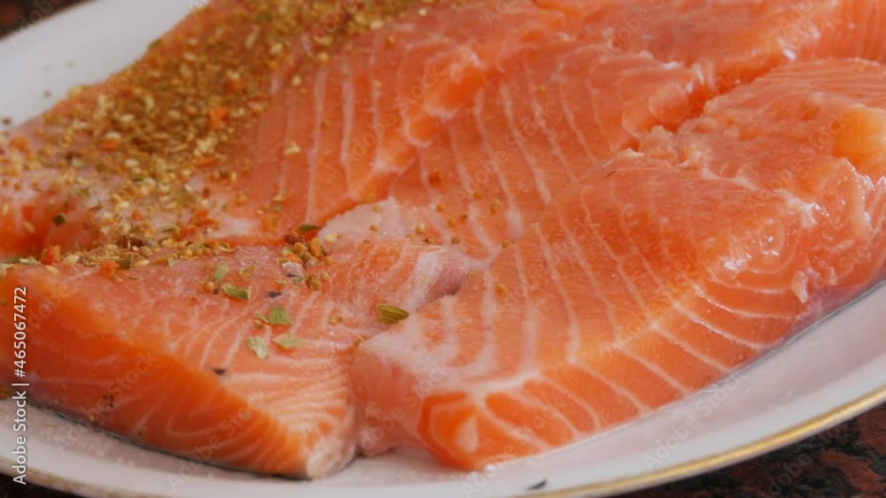 Huge fillet of red fish salmon cut into pieces sprinkle with peppercorn seasoning on a plate Huge fillet of red fish salmon cut into pieces sprinkle with peppercorn seasoning on a plate