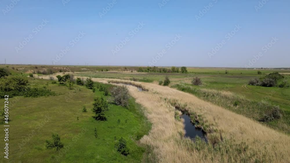 Aerial drone flight along a glossy river with sky reflections, Russia, There are reeds growing on the shore along the water Aerial drone flight along a glossy river with sky reflections, Russia, There are reeds growing on the shore along the water