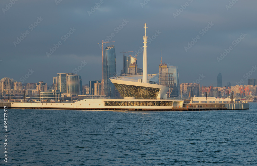 Naklejka premium Lighthouse in the Baku Bay against the background of high-rise buildings under construction, morning haze. Azerbaijan
