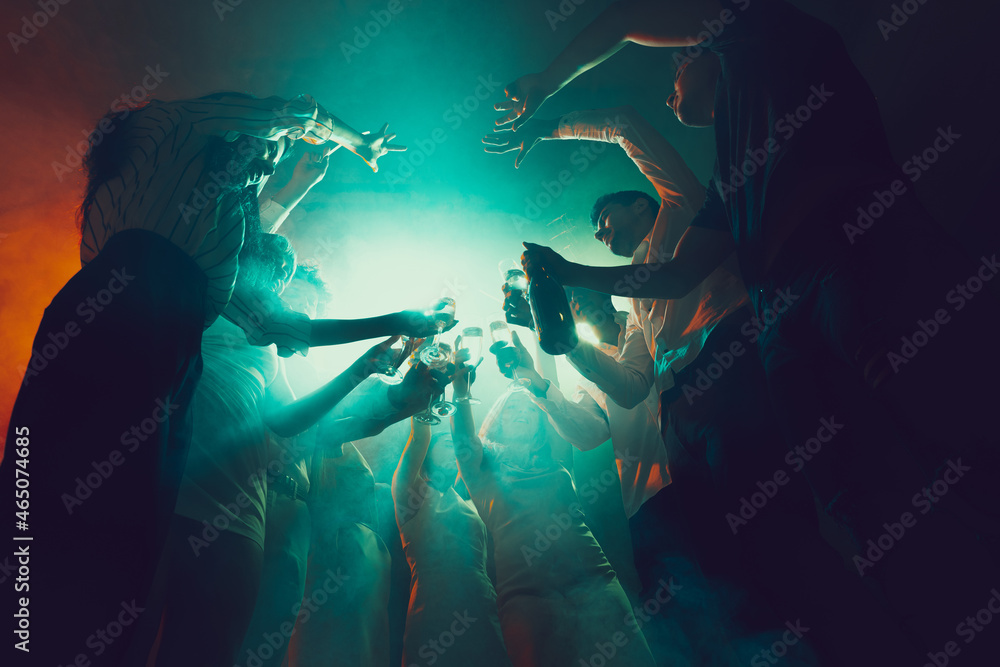 Group of young, active people at the night club, party dancing in neon lights, drinking cocktails - obrazy, fototapety, plakaty 