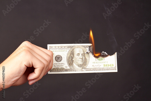 Hand holds burning dollar isolated on a black background.