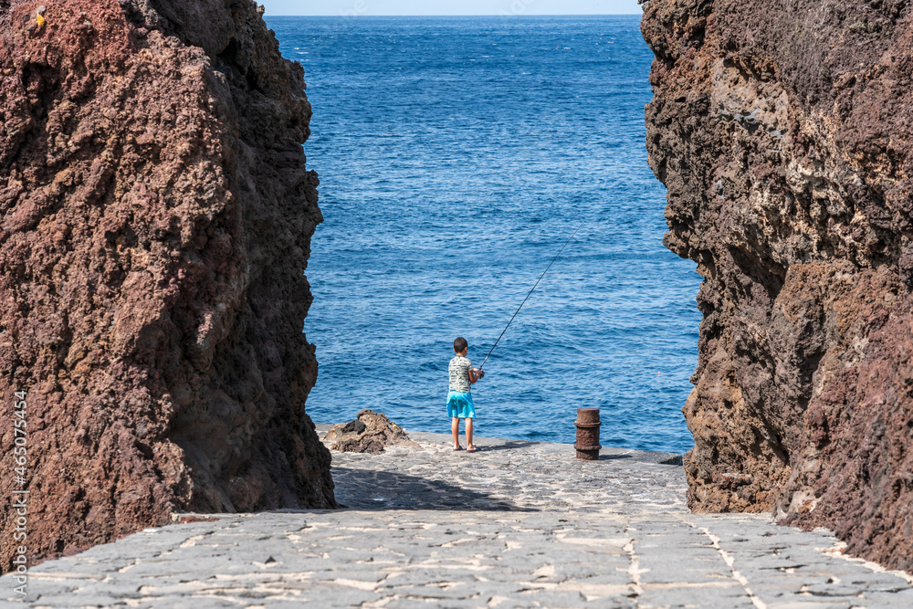 Boy with a fishing rod on the ocean.