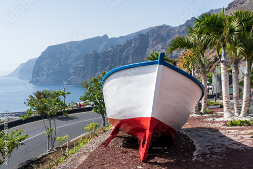 Wooden boat as decoration. The observation deck - Mirador Archipenque. In the background the cliffs of Los Gigantes. Tenerife. Canary Islands. Spain photo