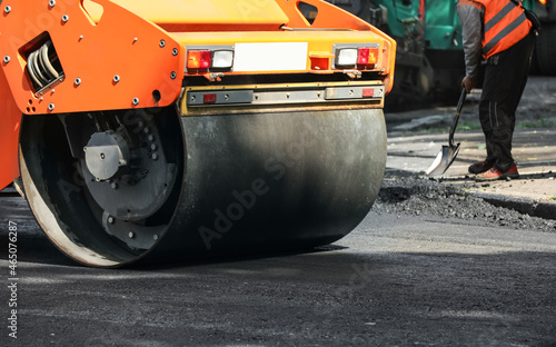 MYKOLAIV, UKRAINE - AUGUST 05, 2021: Worker laying new asphalt with roller on city street. Road repair service © New Africa