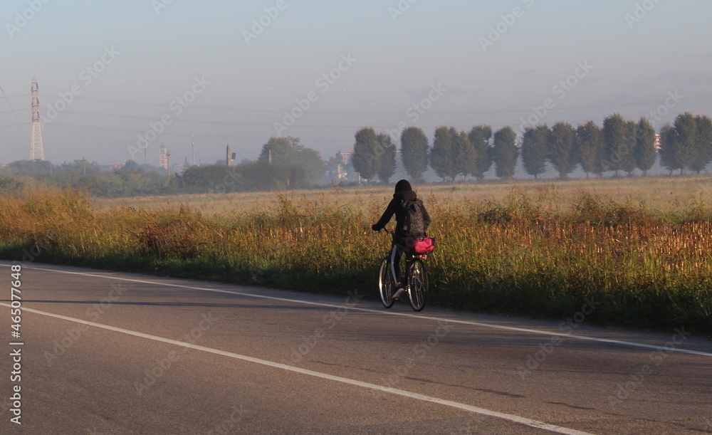Giovane donna che pedala su una strada di campagna Giovane donna che pedala su una strada di campagna
