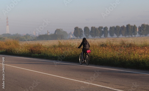 Giovane donna che pedala su una strada di campagna