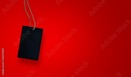Blank black label (tag) hang on bright red background with copy space. Price tag, gift tag, sale tag, address label.