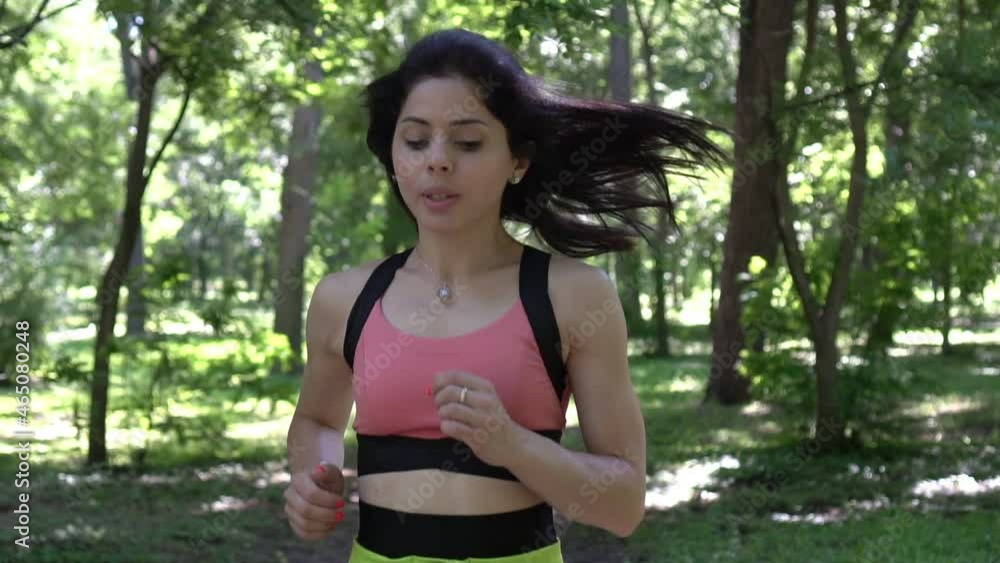 Young active woman jogging in the park. Woman runner on nature in the forest, slow motion Young active woman jogging in the park. Woman runner on nature in the forest, slow motion
