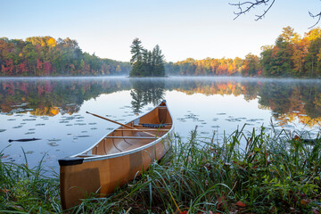 Yellow canoe on shore of beautiful lake with island in northern Minnesota at dawn
