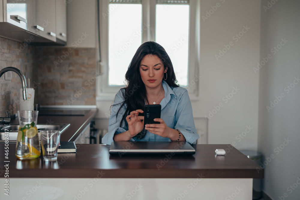 Businesswoman taking selfie with her smartphone while sitting in her kitchen at home Businesswoman taking selfie with her smartphone while sitting in her kitchen at home