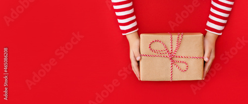 banner gift box in children's hands on a red background, presenting a gift	
 photo