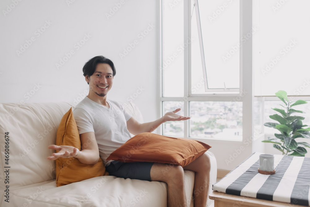 Happy Asian man sits and relax on the sofa in the living room of the apartment. Happy Asian man sits and relax on the sofa in the living room of the apartment.
