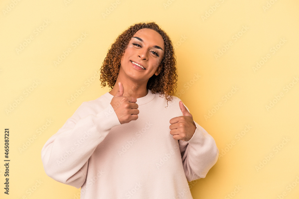 Young latin transsexual woman isolated on yellow background raising both thumbs up, smiling and confident. Young latin transsexual woman isolated on yellow background raising both thumbs up, smiling and confident.