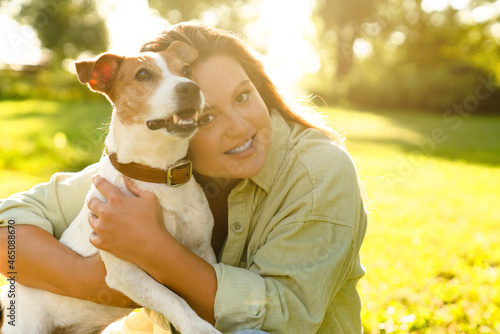 Love and care. Pet adoption concept. Young caucasian pet owner hugging embracing little cute small jack russell terrier walking in park photo