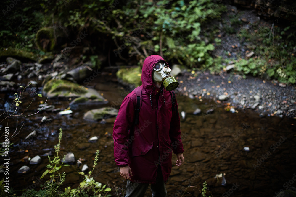 Ecological catastrophy. Post apocalyptic survivor in gas mask. Man at forest.