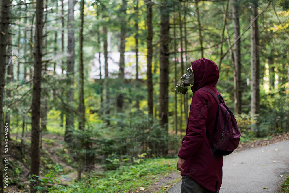casual young man in a gas mask standing on the forest. Ecological catastrophy. Post apocalyptic survivor in gas mask. Man at forest. casual young man in a gas mask standing on the forest. Ecological catastrophy. Post apocalyptic survivor in gas mask. Man at forest.