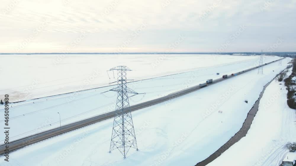 Aerial view over Power lines with towers near road with traffic in winter Aerial view over Power lines with towers near road with traffic in winter