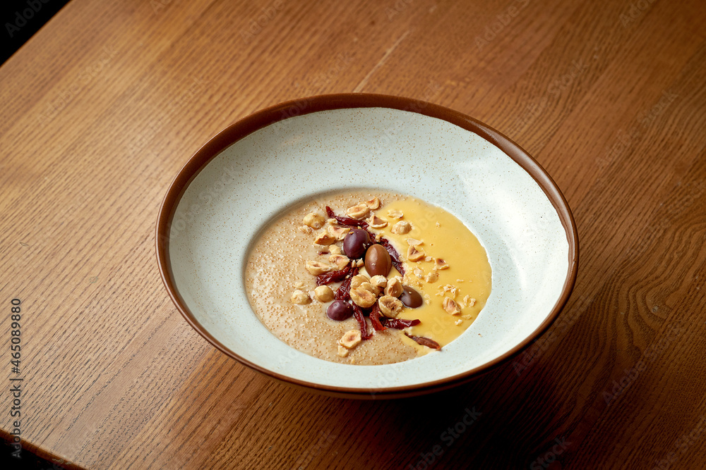 Amaranth porridge with cheese sauce and nuts in a white plate on a wooden background Amaranth porridge with cheese sauce and nuts in a white plate on a wooden background