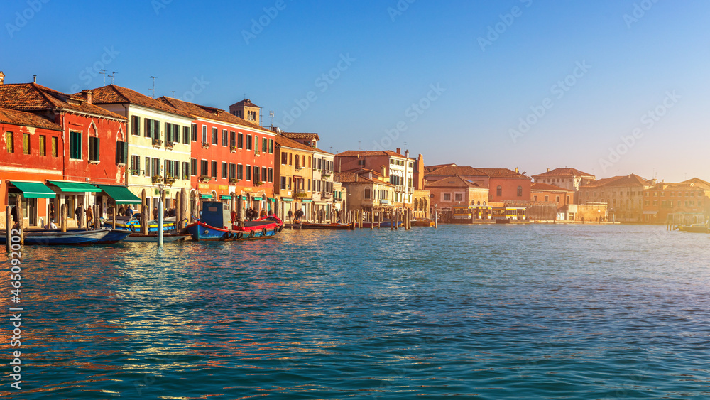 Murano glass making island, water canal, bridge, boat and traditional buildings. Venice or Venezia, Italy, Europe.
