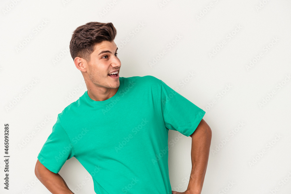 Obraz premium Young caucasian man isolated on white background laughs happily and has fun keeping hands on stomach.