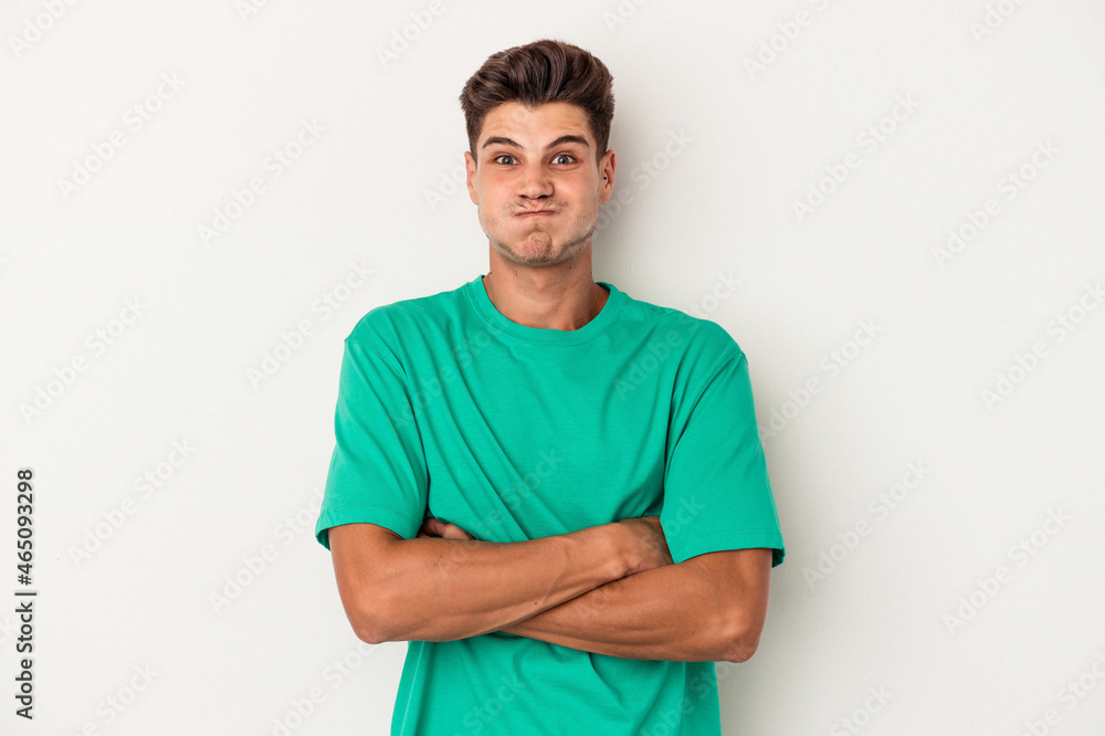 Obraz premium Young caucasian man isolated on white background blows cheeks, has tired expression. Facial expression concept.