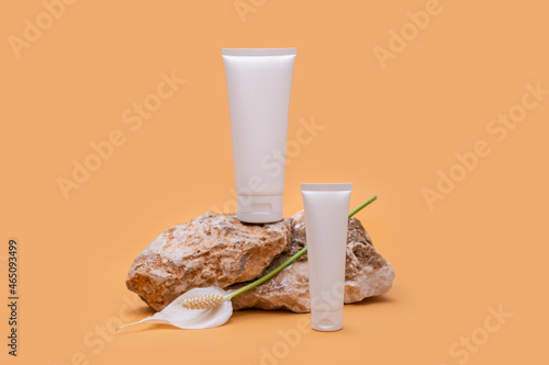 Two white tubes of cream or body lotion on a pieces of stone on a beige background. Natural cosmetic. Treatment spa beauty skincare. Healthcare and medicine concept. Modern still life product photo 