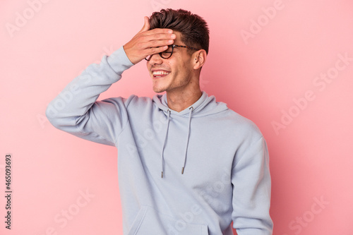 Young caucasian man isolated on pink background covers eyes with hands, smiles broadly waiting for a surprise. © Asier