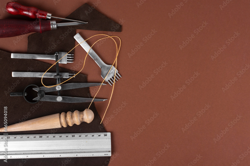 Leather and craft tools on brown background