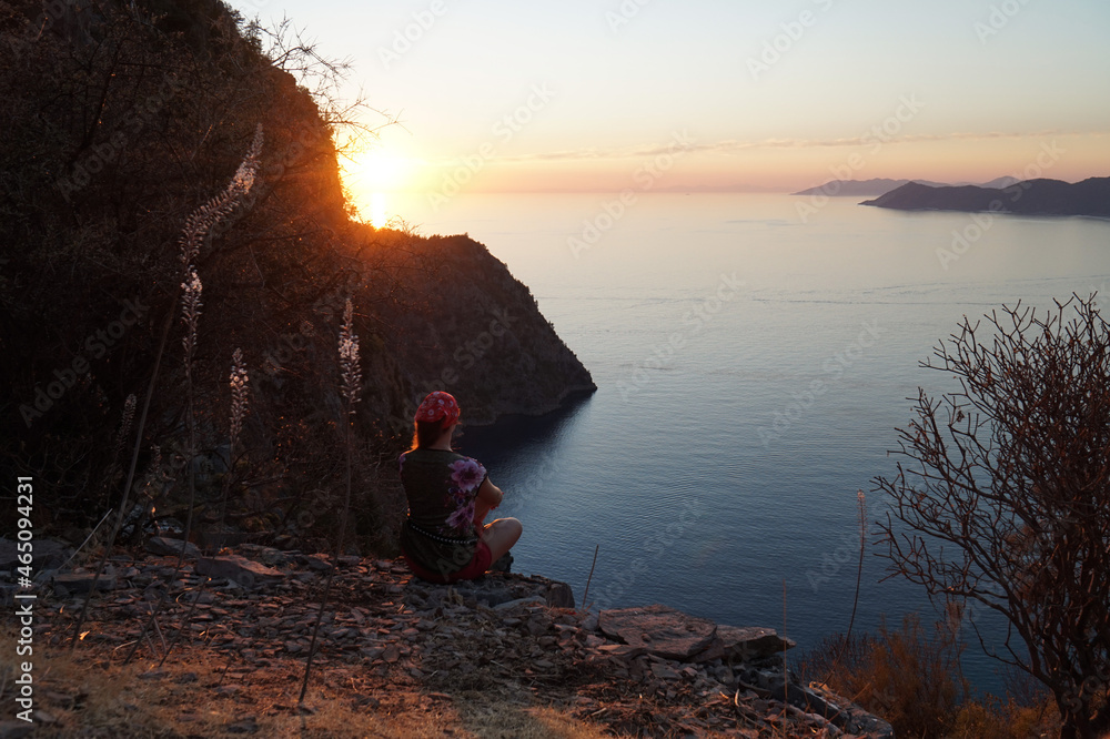 The girl admires the sunset over the Valley of the Butterflies from above. South of Turkey.     