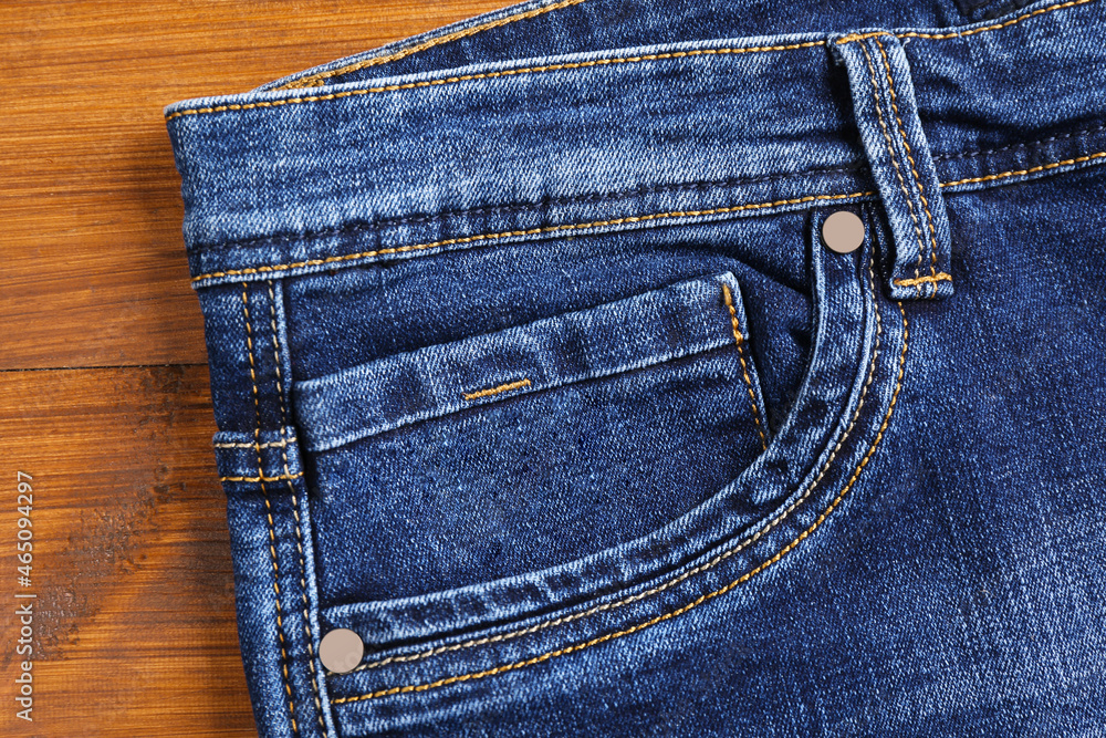 Stylish blue jeans on wooden background, closeup of inset pocket Stylish blue jeans on wooden background, closeup of inset pocket