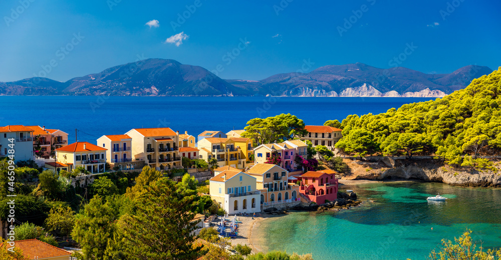 Turquoise colored bay in Mediterranean sea with beautiful colorful houses in Assos village in Kefalonia, Greece. Town of Assos with colorful houses on the mediterranean sea, Greece.