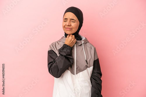 Young Arab woman with sport burqa isolated on pink background suffers pain in throat due a virus or infection.