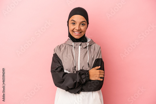 Young Arab woman with sport burqa isolated on pink background laughing and having fun.
