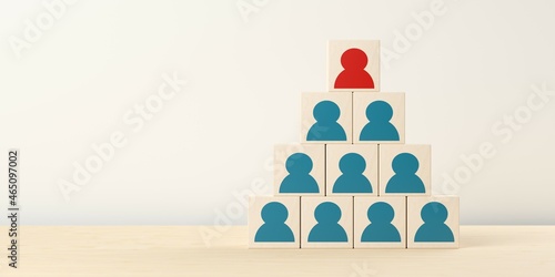 Pyramid of wooden blocks with blue figure icons and red icon on top, team lead or business management success concept photo
