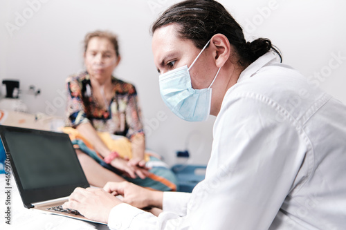 Middle-aged latin doctor at home checking exams on laptop
