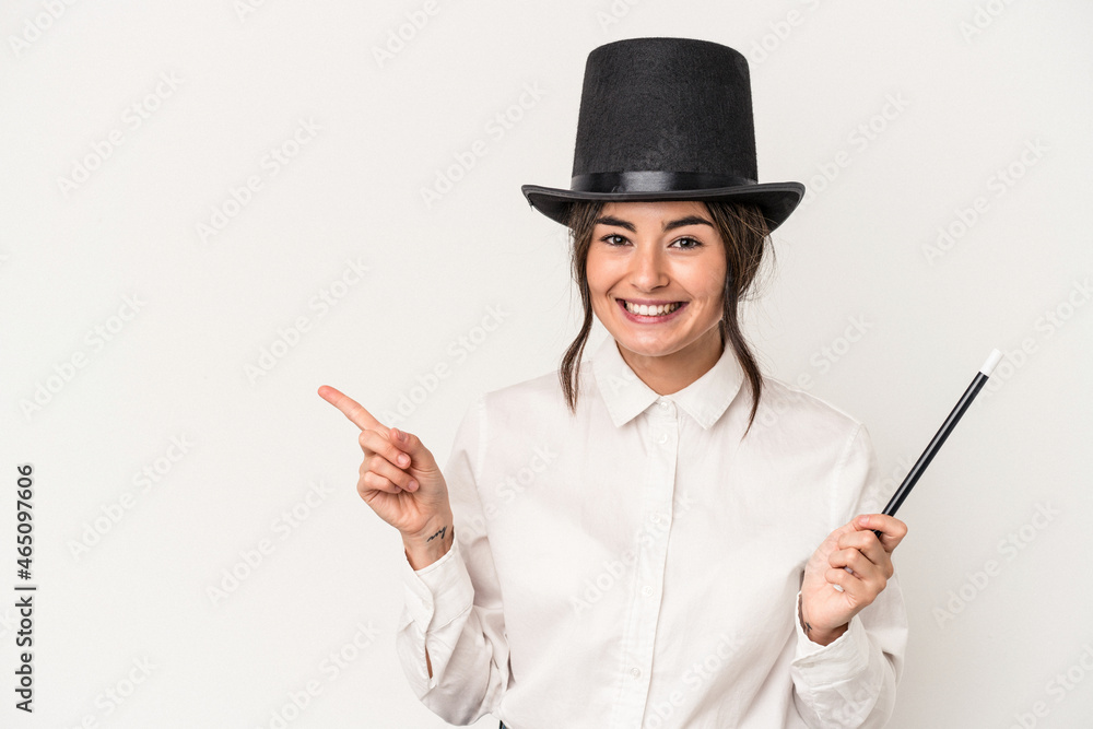Young magician woman holding a wand isolated on white background smiling and pointing aside, showing something at blank space. Young magician woman holding a wand isolated on white background smiling and pointing aside, showing something at blank space.
