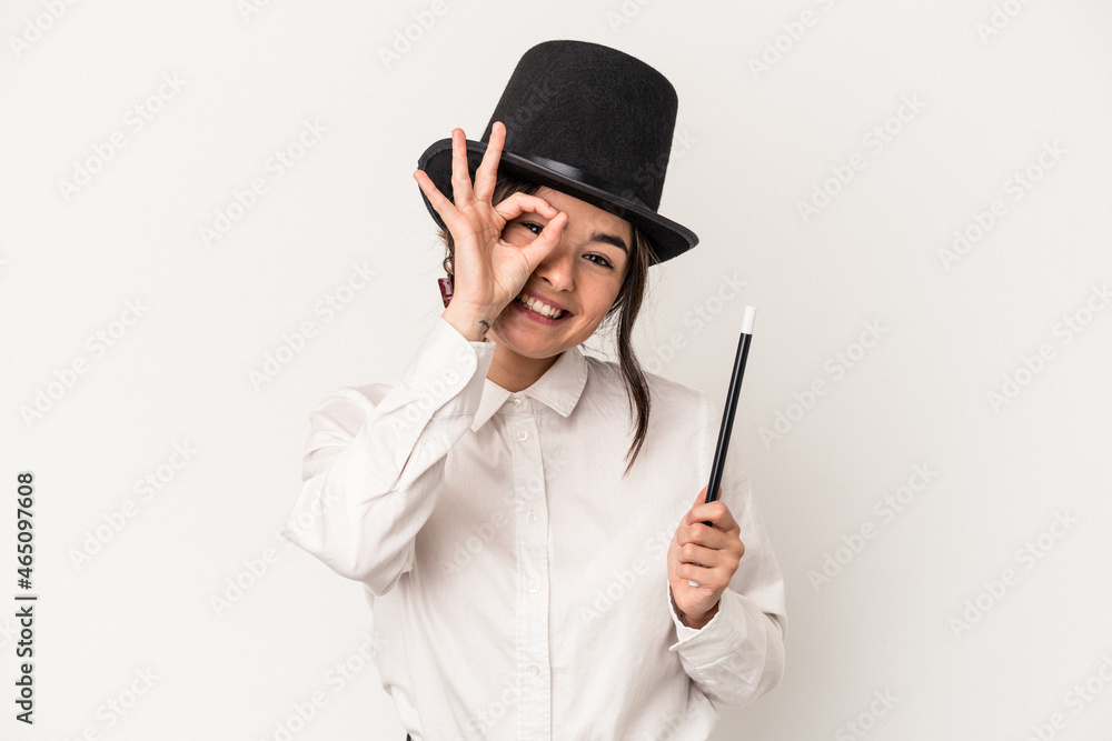 Young magician woman holding a wand isolated on white background excited keeping ok gesture on eye. Young magician woman holding a wand isolated on white background excited keeping ok gesture on eye.